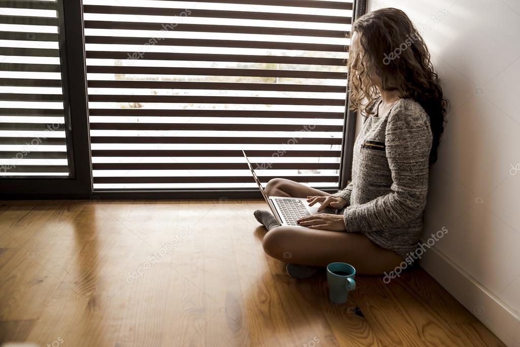 Woman Working on a laptop sitting on floor