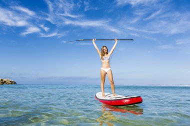 Woman with arms up and learning paddle-surf