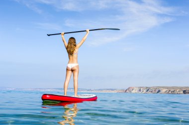 Woman with arms up and learning paddle-surf