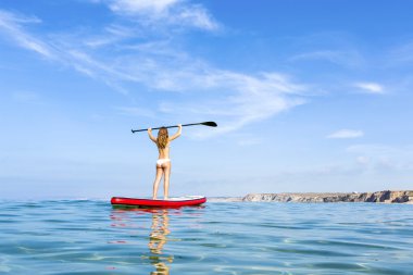 Woman with arms up and learning paddle-surf