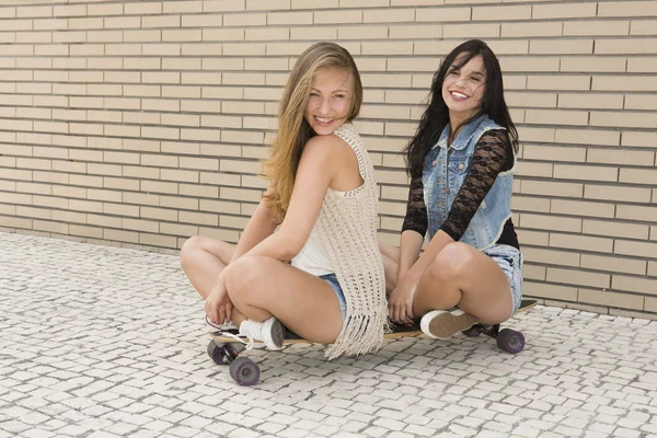 Namoradas se divertindo com um skate — Fotografia de Stock