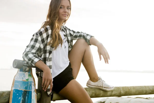 Jonge vrouw poseren met een skateboard — Stockfoto