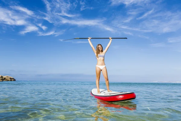 Woman with arms up and learning paddle-surf — Stok fotoğraf