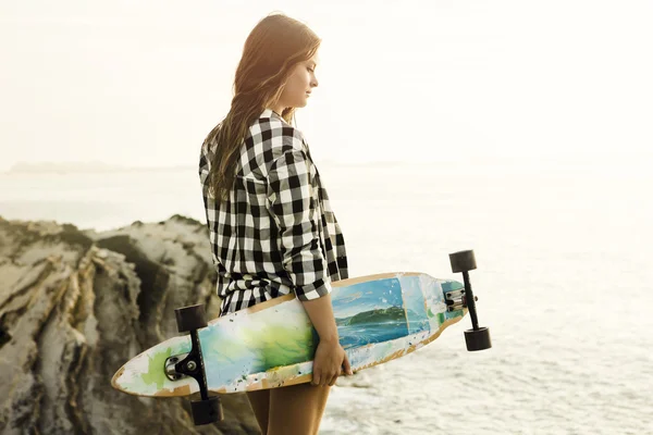 Giovane donna in posa con uno skateboard — Foto Stock