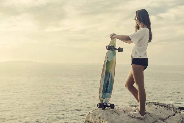 Giovane donna in posa con uno skateboard — Foto Stock