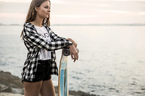 Giovane donna in posa con uno skateboard — Foto Stock