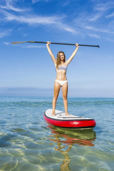 Woman with arms up and learning paddle-surf — Stock Photo, Image