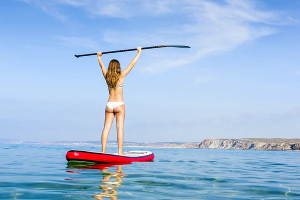 Donna con le braccia alzate e imparare paddle-surf — Foto Stock