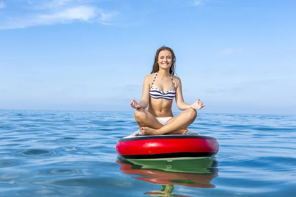 Mujer relajándose sobre una tabla de surf de paddle — Foto de Stock