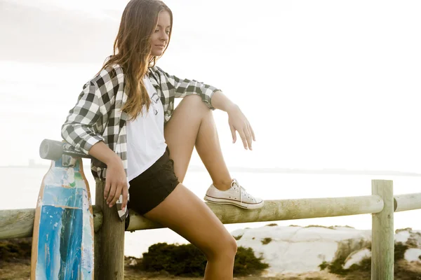 Giovane donna in posa con uno skateboard — Foto Stock