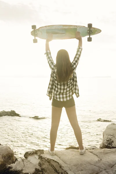 Giovane donna in posa con uno skateboard — Foto Stock