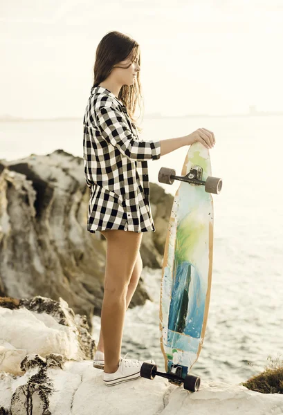 Giovane donna in posa con uno skateboard — Foto Stock