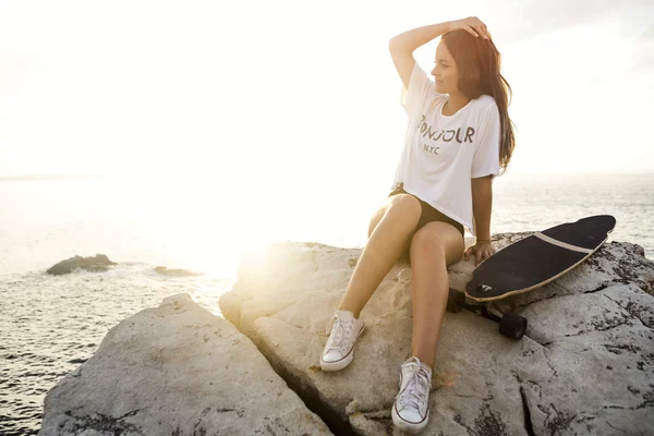 Giovane donna in posa con uno skateboard — Foto Stock