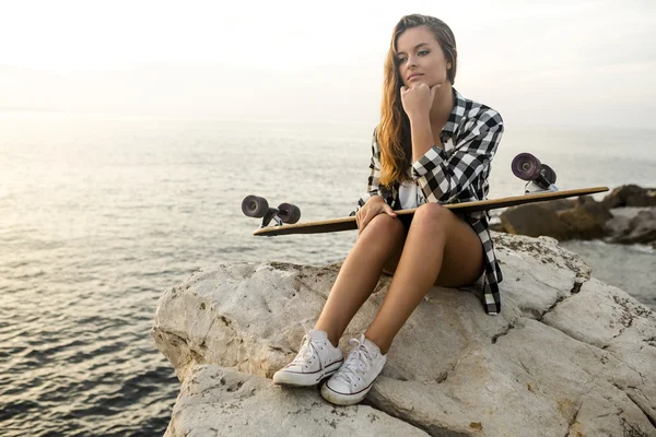 Giovane donna in posa con uno skateboard — Foto Stock