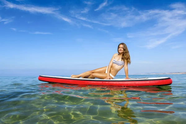 Woman sitting over a paddle surfboard — Stock Photo, Image