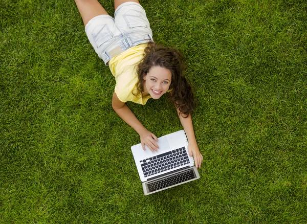 Mulher trabalhando com um laptop na grama — Fotografia de Stock