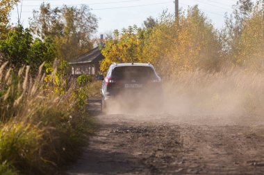 VOLKOVO, RUSSIA - 4 Ekim 2020: Mavi Nissan Qashqai tekerlerden gelen toz bulutuyla toprak yolda ilerliyor.