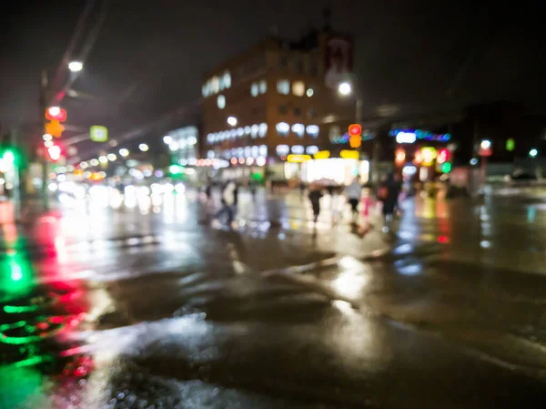 defocused night rain city street view with cars crossing road