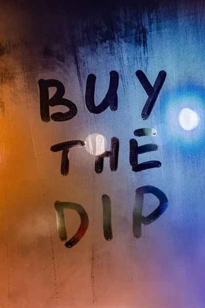 Phrase buy the dip handwritten on night wet window glass surface — Stock Photo, Image