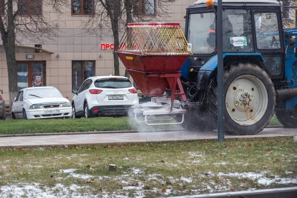 TULA, RUSIA - 21 de noviembre de 2020: Tractor esparciendo reactivo de sal en el pavimento de la ciudad a la luz del día de invierno. — Foto de Stock