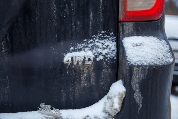 Uma abreviatura 4wd - tração nas quatro rodas - no carro preto sujo de volta — Fotografia de Stock