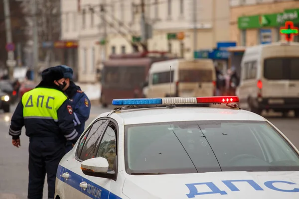 Russische Verkehrspolizisten stehen neben Streifenwagen auf winterlicher Straße - Nahaufnahme mit selektivem Fokus auf Dachlaterne. — Stockfoto