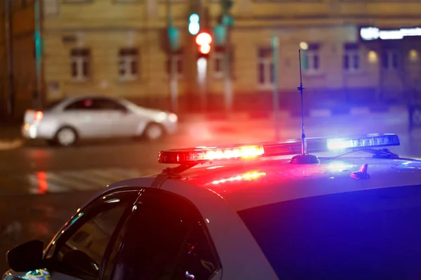 Lampu mobil polisi malam di jalan kota dengan mobil sipil di latar belakang kabur Stok Gambar Bebas Royalti