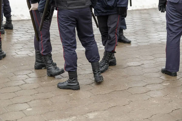 Російські поліцейські ноги в чорних чоботах на щиколотках, червоні смугасті штани і з гумовими нічними палицями.. — стокове фото