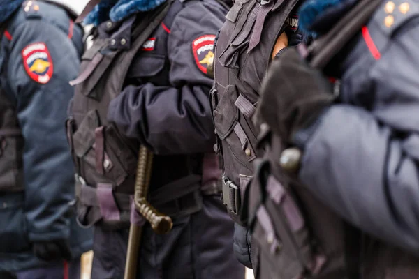 Siyah üniformalı, kurşun geçirmez yelekli polis memurları. Siyah eldivenlere yakından bakıyorlar.. — Stok fotoğraf