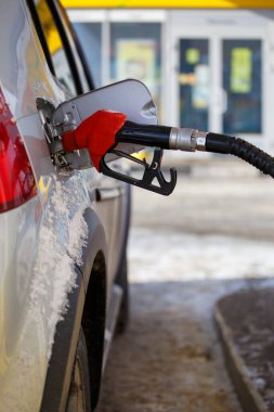 Gümüş metalik araba kış günü benzin ikmali yapıyor. Yakın plan seçici odaklanma ve bulanık arka plan ile.