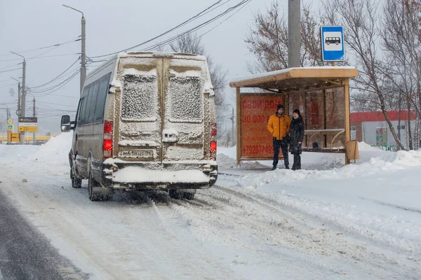 Hombre y mujer esperando transporte en parada de autobús en invierno día nevado en Tula, Rusia — Foto de Stock