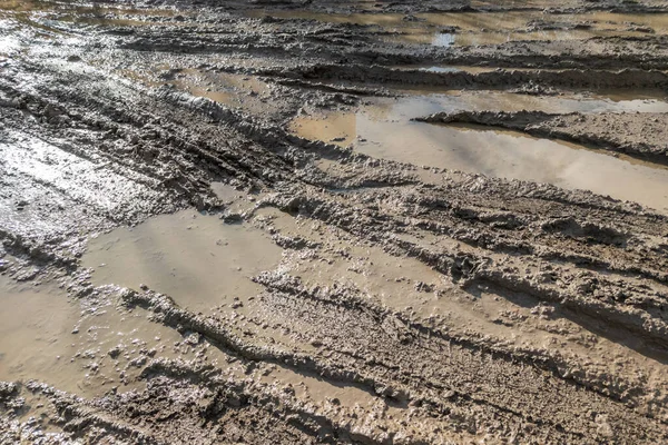 Strada fango argilla sporca con tracce di pneumatici durante il giorno - sfondo pieno telaio con luce del sole dura — Foto Stock