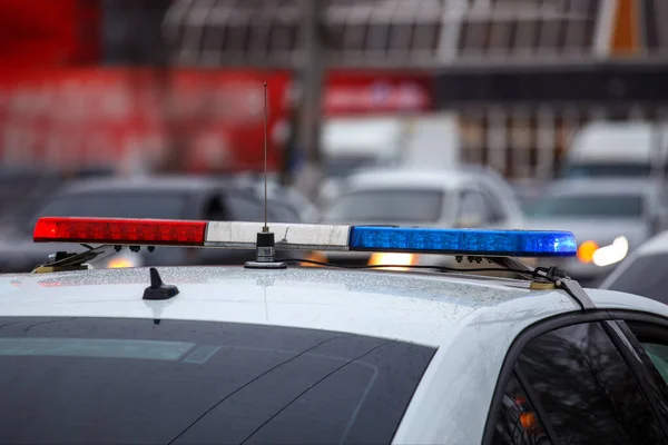 Police car lights in city street at winter day with cars traffic in blurry background — Stock Photo, Image