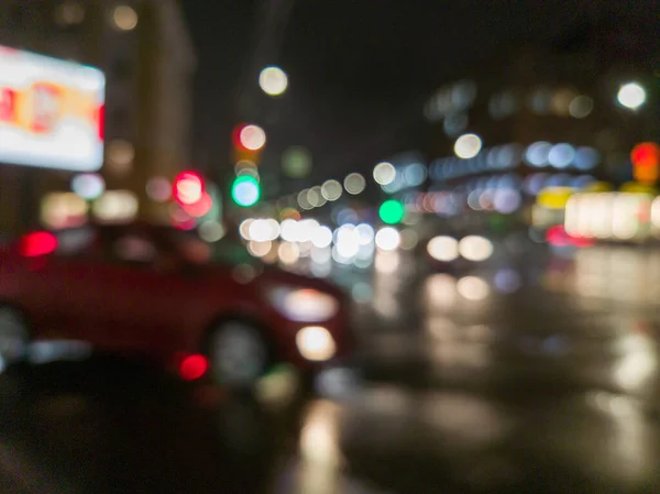 defocused night rain city street cross roads view with red car