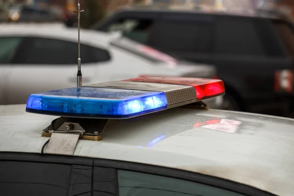 Police car lights in city street at winter day with cars traffic in blurry background — Stock Photo, Image