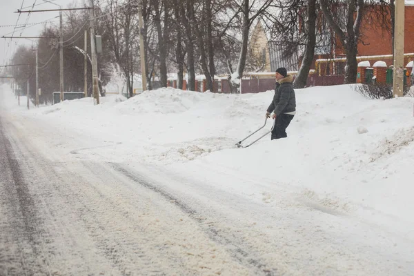 Tula, Rusia - 13 de febrero de 2020: Camino de entrada de limpieza del hombre con rascador de nieve en la mañana de invierno después de la tormenta de nieve. — Foto de Stock