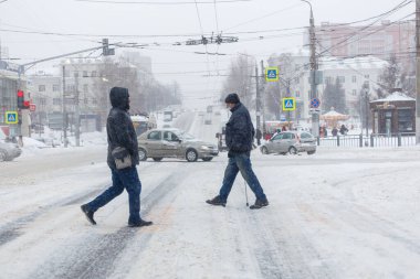 Tula, Rusya - 13 Şubat 2020: Şiddetli kar yağışı sırasında iki adam şehir yolunu geçiyor.
