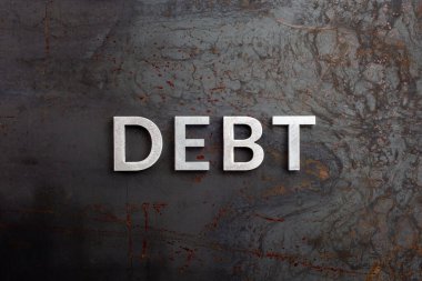 Borç kelimesi gümüş harflerle işlenmemiş çelik levha yüzeyinde düz bir perspektifte yatıyordu.
