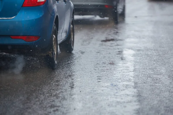 Vuil water spatten stroom van wielen van de blauwe auto snel in daglicht stad met selectieve focus. — Stockfoto