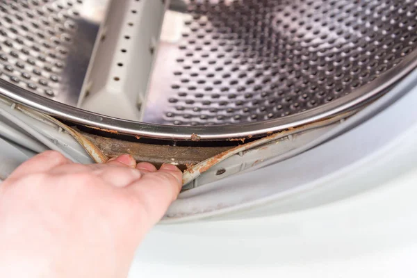 Рука виступає гумовою стрічкою барабану пральної машини з шаром бруду під — стокове фото