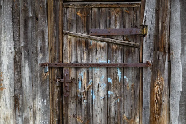 Altes hölzernes Scheunentor mit eisernen Vorhängeschlössern und rostigen Stahlbewehrungsbändern — Stockfoto