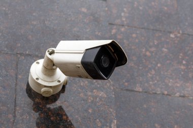 small cheap surveillance camera on tan brown granite wall clipart