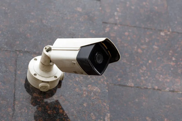 Small cheap surveillance camera on tan brown granite wall — Stock Photo, Image