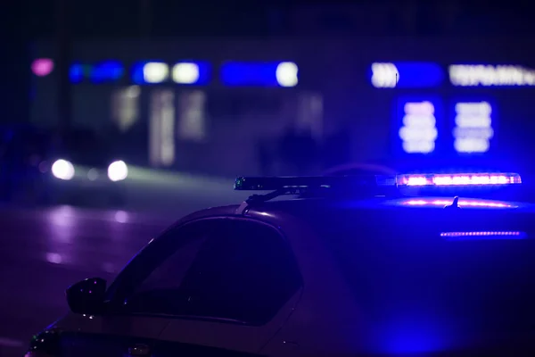 Lumière bleue de voiture de police la nuit dans la ville avec un accent sélectif et bokeh sur fond noir — Photo