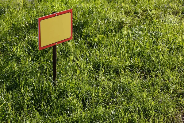 Blank żółty znak makieta na zielonym tle trawnika - zbliżenie z selektywnym ostrością — Zdjęcie stockowe
