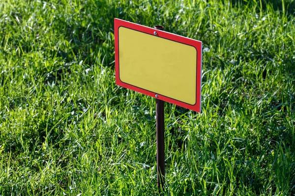 Blank żółty znak makieta na zielonym tle trawnika - zbliżenie z selektywnym ostrością — Zdjęcie stockowe