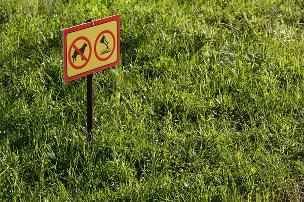 Yellow sign with chemical application no dogs on green lawn background - close-up with selective focus — Stock Photo, Image