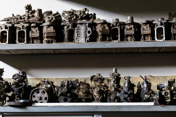 Old dirty metal engine parts on dark garage shelf — Stock Photo, Image