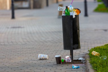 Yaz güneşinde kaldırımda taşan çöp tenekesi.
