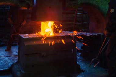 Büyük mekanik çekiç makinesi ile sıcak çelik elle dövülme işleminin yakın plan resmi